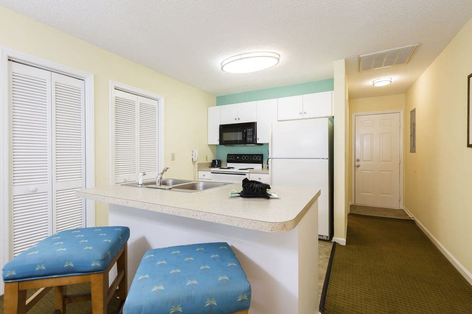 The fully-equipped kitchen with modern appliances and a breakfast bar invites you to prepare meals in comfort during your stay at this charming condo.