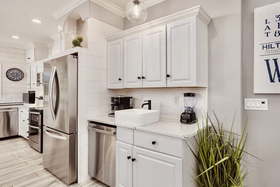 The fully-equipped kitchen has brand new stainless steel appliances. To the right of the French door refrigerator is a beverage area with a Keurig K-Duo, sink, blender and dishwasher.