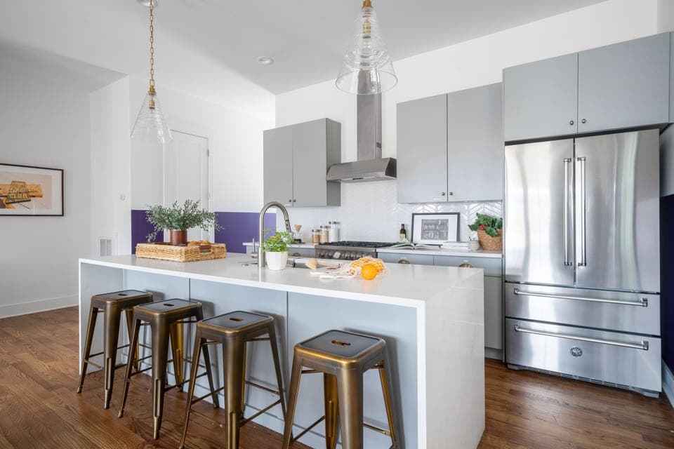 Kitchen features an island with barstool seats and modern appliances. (Faith)