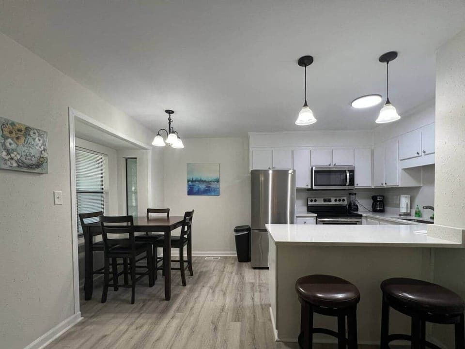 This fully equipped kitchen features stainless steel appliances, a large counter with seating, and a cozy dining nook framed by natural light. Whether you’re cooking a full meal or enjoying takeout, this space is perfect for gathering and dining in.