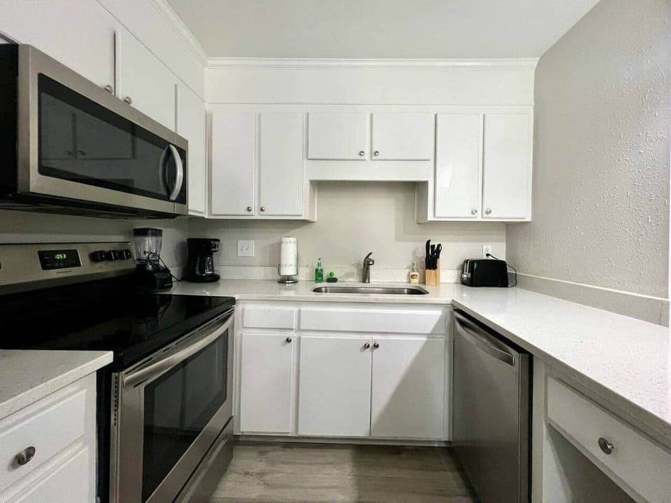 This fully equipped kitchen features stainless steel appliances, a large counter with seating, and a cozy dining nook framed by natural light. Whether you’re cooking a full meal or enjoying takeout, this space is perfect for gathering and dining in.