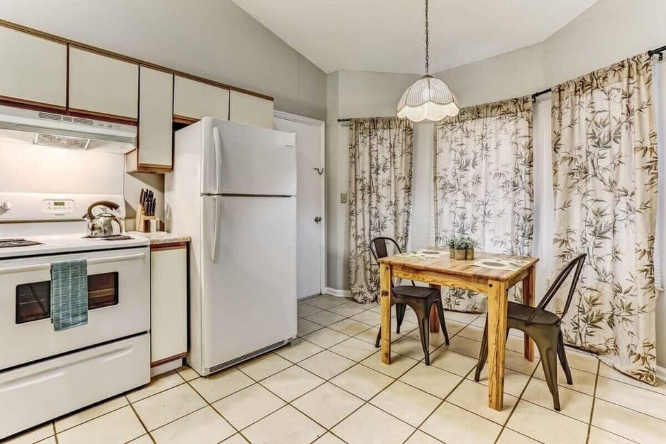 Bright kitchen with white cabinets and full-size appliances.