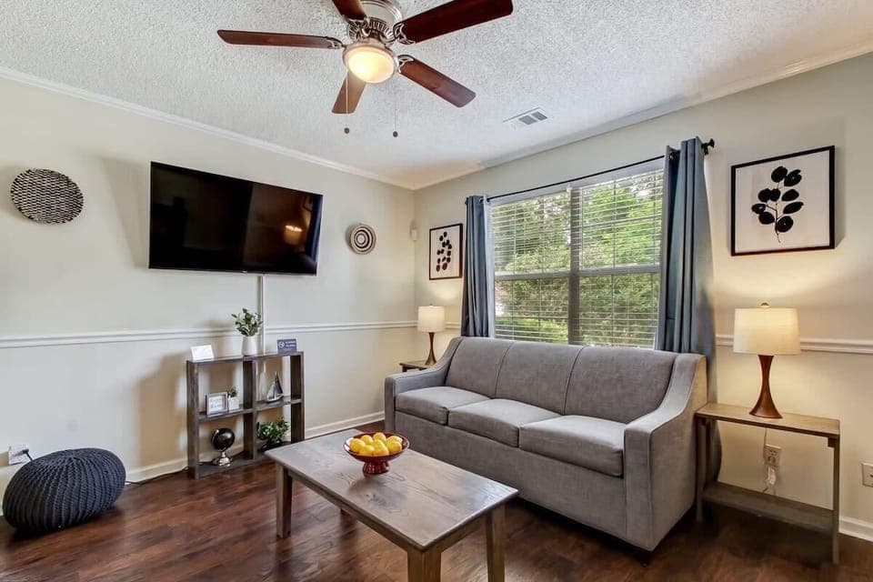 The living room features a cozy sofa, a Roku TV, and plenty of natural light.
