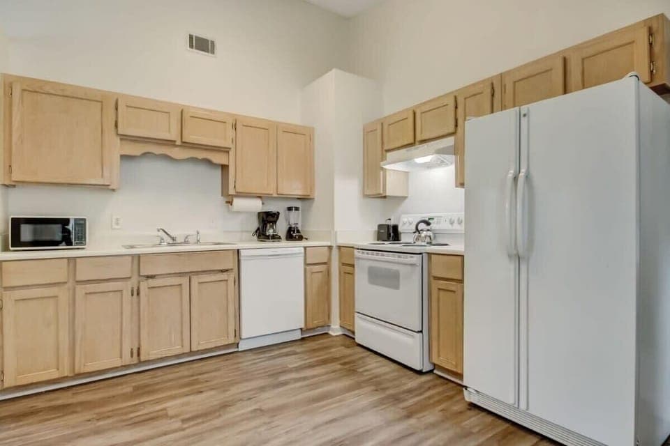 The kitchen features light wood cabinets, full-size appliances, and ample counter space.