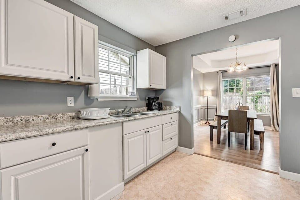 Modern kitchen with white cabinetry and marble-look countertops.