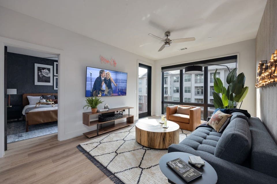 Unit 3: Modern open concept living area with floor to ceiling windows, designer furniture, smart TV, and access to private patio.