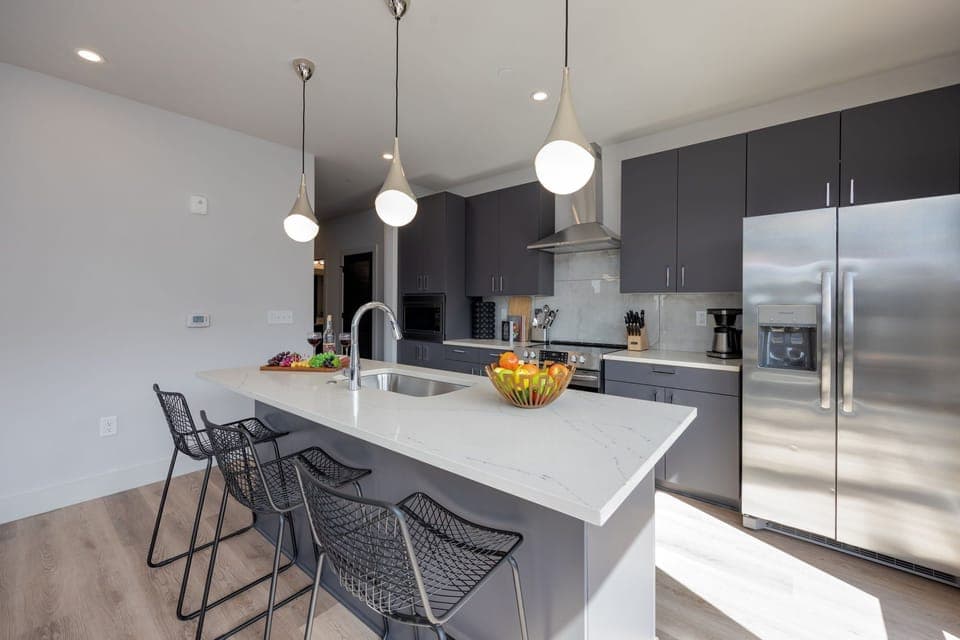 Unit 1: Fully equipped kitchen stocked with basic cooking essentials. Includes stainless steel appliances and kitchen island seating.