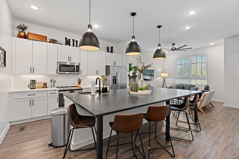 Modern white kitchen featuring stainless steel appliances and a central island.