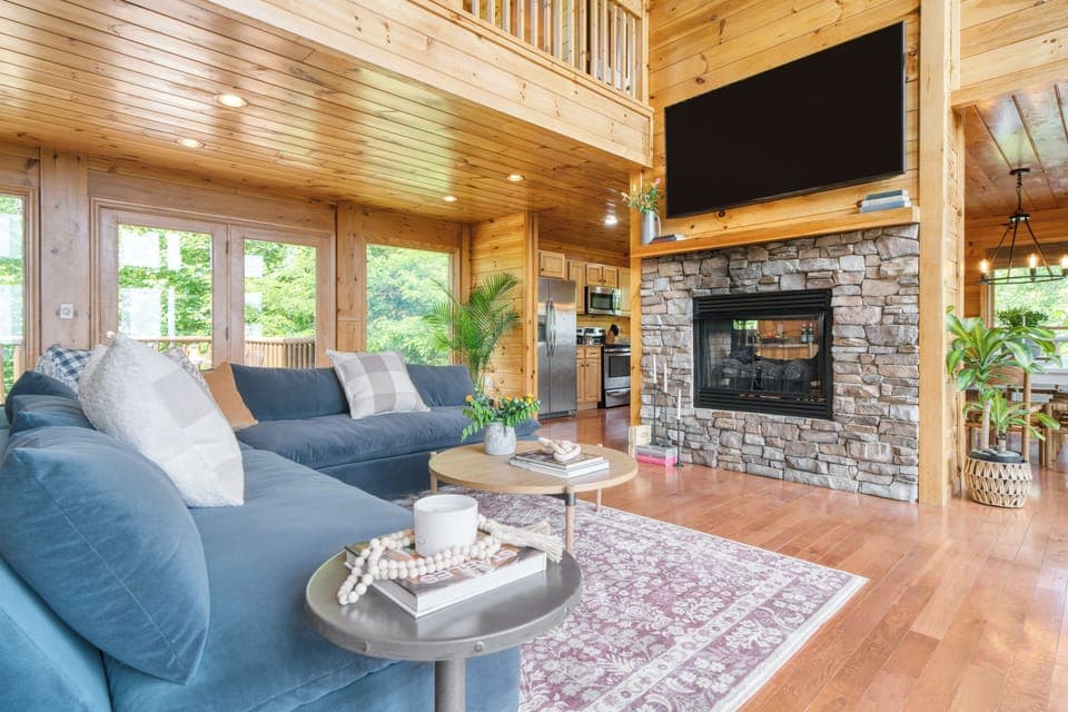 Spacious living room with vaulted ceilings and a fireplace. (Hollow's Haven)