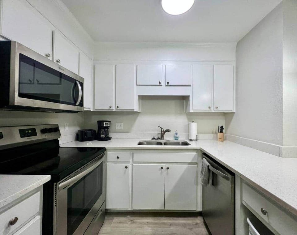 This fully equipped kitchen features stainless steel appliances, a large counter with seating, and a cozy dining nook framed by natural light. Whether you’re cooking a full meal or enjoying takeout, this space is perfect for gathering and dining in.
