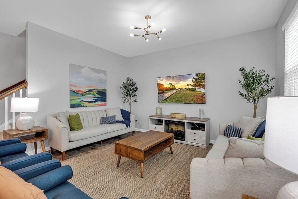 Cozy living room with natural light, comfy seating, and a smart TV for relaxing.