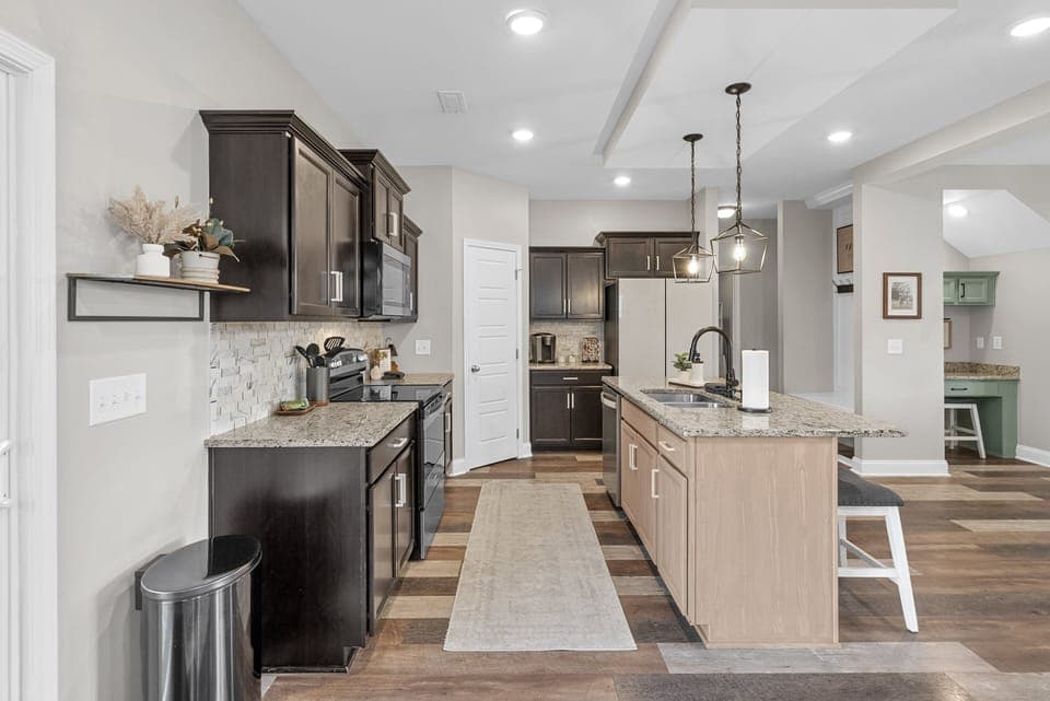 Modern kitchen with granite countertops, island seating, and stainless steel appliances