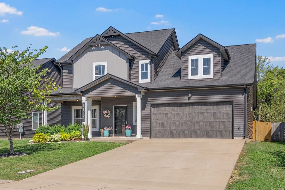 Full front view of home with covered porch and two car garage