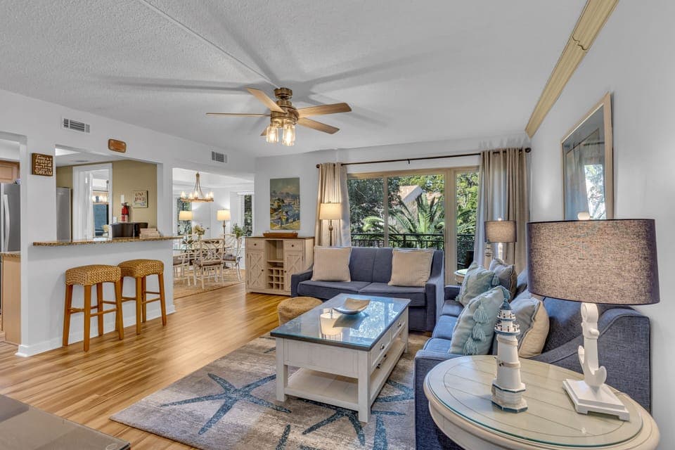 Relax in your spacious living area with soaring ceilings, warm wood floors, and a cozy ceiling fan creating the perfect atmosphere.