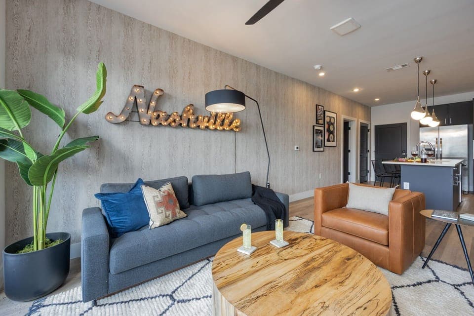 Unit 3: Open concept living area with smart TV, comfortable seating, designer decor, natural lighting, and access to private patio.