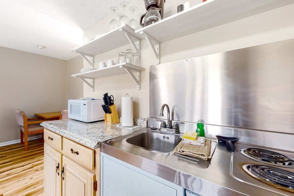 Stocked kitchenette with cooktop, sink, microwave, coffee setup, dishes & glassware. Perfect for extended stays and easy meals. Studio suite with mini kitchen, convenient amenities, and quick dining.