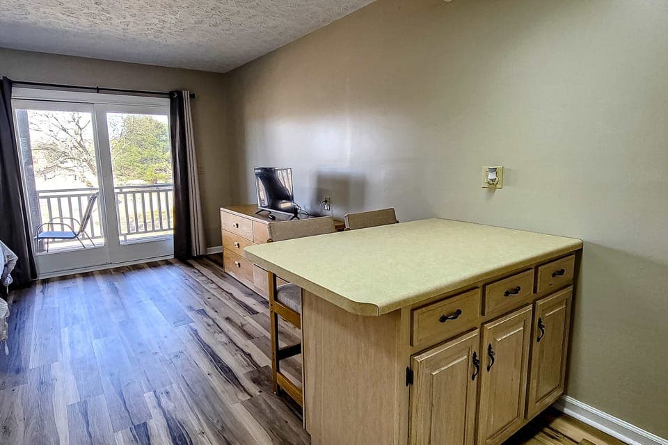 Bright studio with dining island, smart TV & balcony access. Fresh air and views. Great for long-stay, work trips, extended stay, couples getaway, clean modern room.