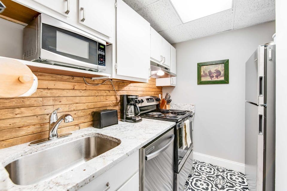 Fully equipped kitchen with stainless steel appliances, microwave, dishwasher, coffee maker, and modern countertops. Perfect for cooking meals during your Smoky Mountains getaway, Gatlinburg vacation, or Pigeon Forge stay.