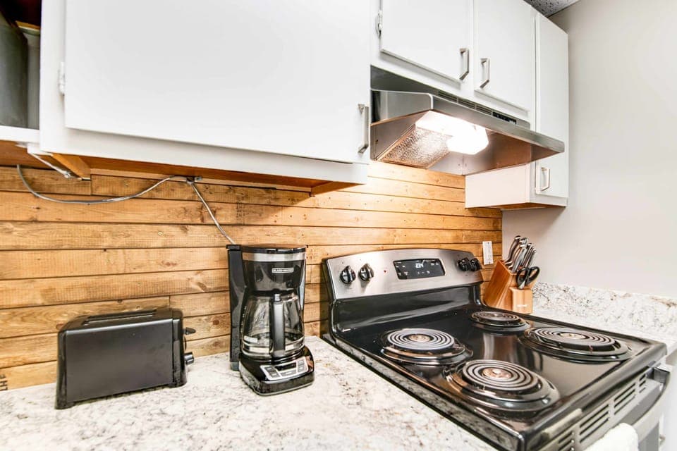 Clean and functional kitchen featuring coffee maker, toaster, stove, knife set, and ample counter space. Perfect for short or extended stays in the Smoky Mountains near Gatlinburg.