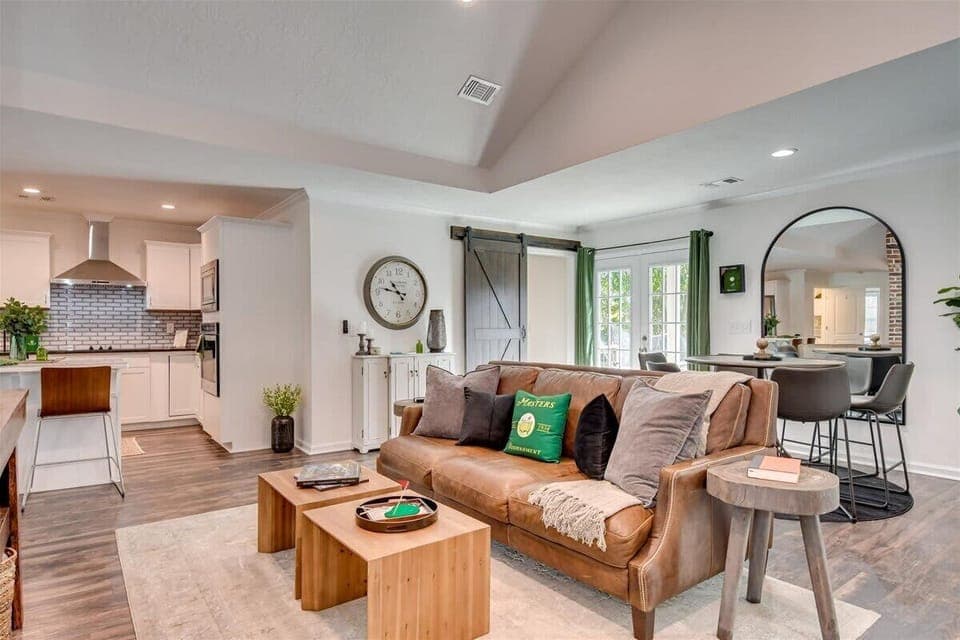 Bright and airy open-concept living space featuring a stylish leather sofa, modern decor, and a cozy dining area on the side.