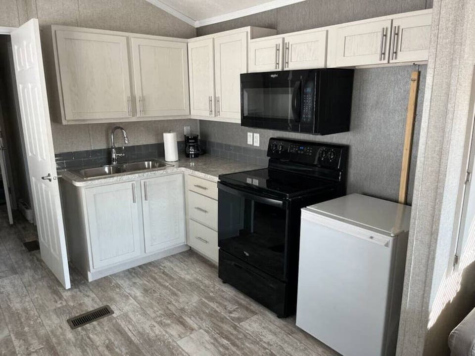A clean, modern kitchen designed for simple, stress-free cooking. It features a drip coffee maker, full stove/oven, and fridge, with plenty of cabinet space and a sleek, uncluttered layout—perfect for easy meals, morning coffee, and relaxed stays.