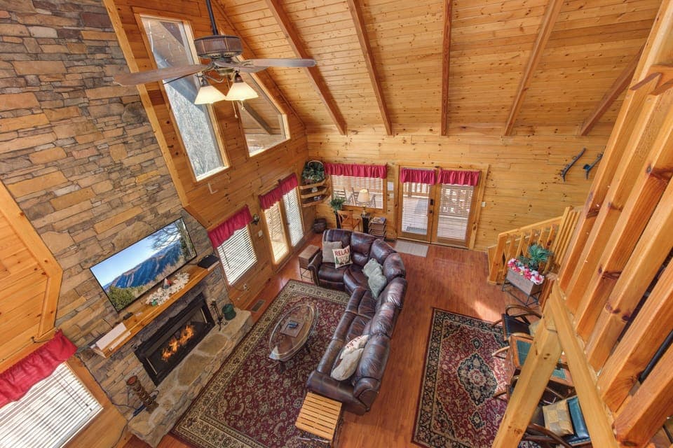 Cozy up in your mountain retreat's living room with soaring timber ceilings, crackling stone fireplace, and leather seating perfect for relaxing evenings.