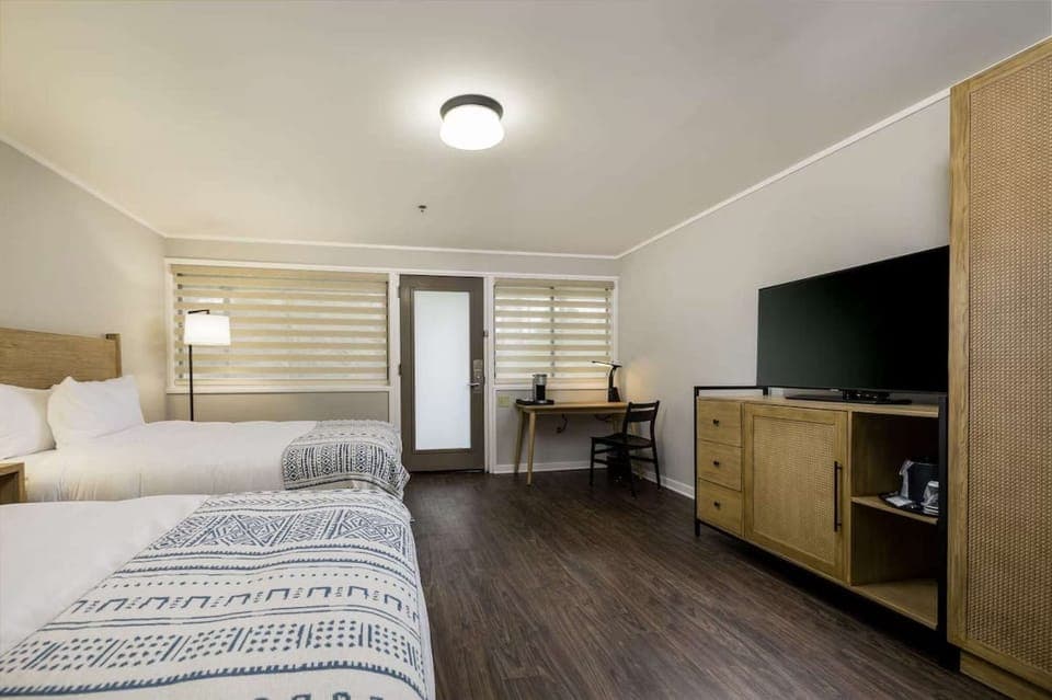 Queen bed room with TV, desk, and natural light