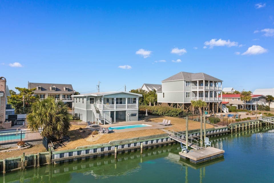 Coastal rental community featuring waterfront homes, private docks, swimming pools, and palm trees along scenic canal waters.