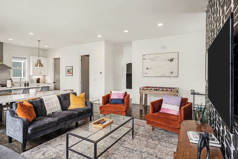 Open-concept living with foosball table, plush seating, and a bright, modern kitchen. | Unit A