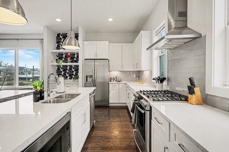 Open-concept kitchen with quartz counters, gas range, and stainless appliances. | Unit A