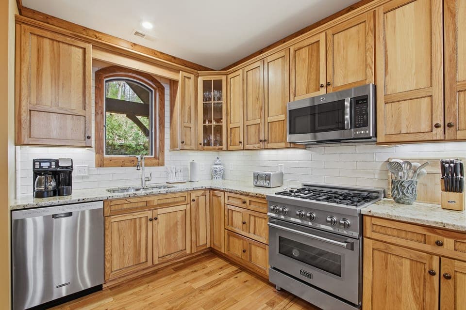 Chef's kitchen with gas range, granite counters, and arched window
