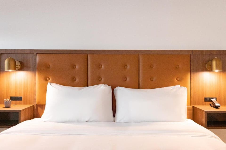 Sink into crisp linens under warm, designer bedside lighting.