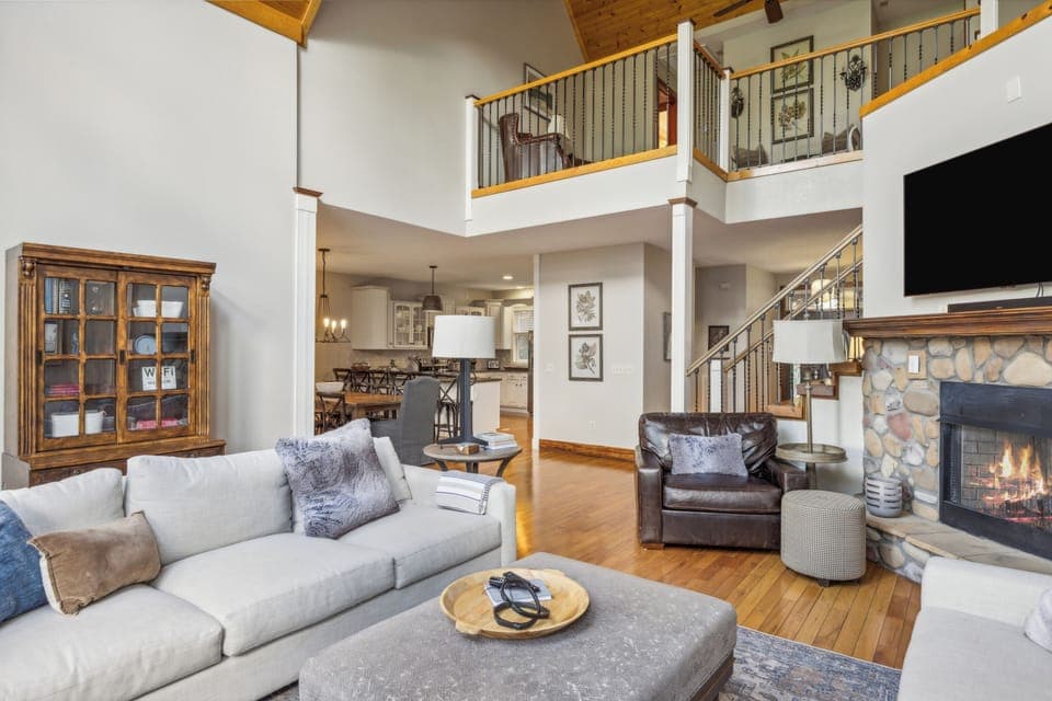 Open living area with stone fireplace and loft above.