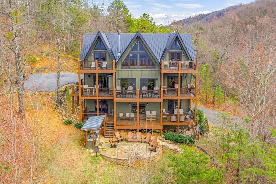 Stunning mountain chalet with multiple decks overlooks vibrant autumn foliage in a secluded valley setting.