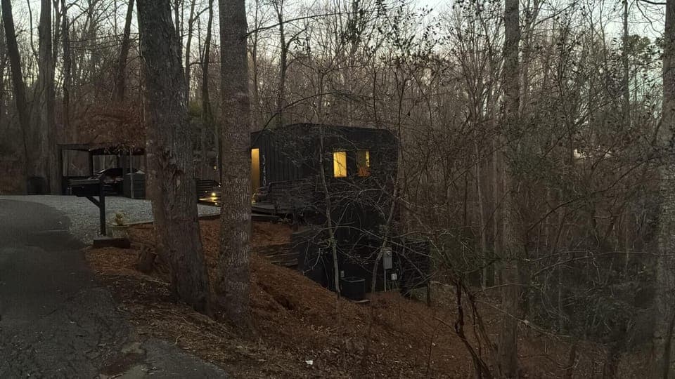 The apartment glows warmly in the evening, surrounded by acres of peaceful woodland. Convenient gravel parking offers space for three or more vehicles, combining privacy with easy access.