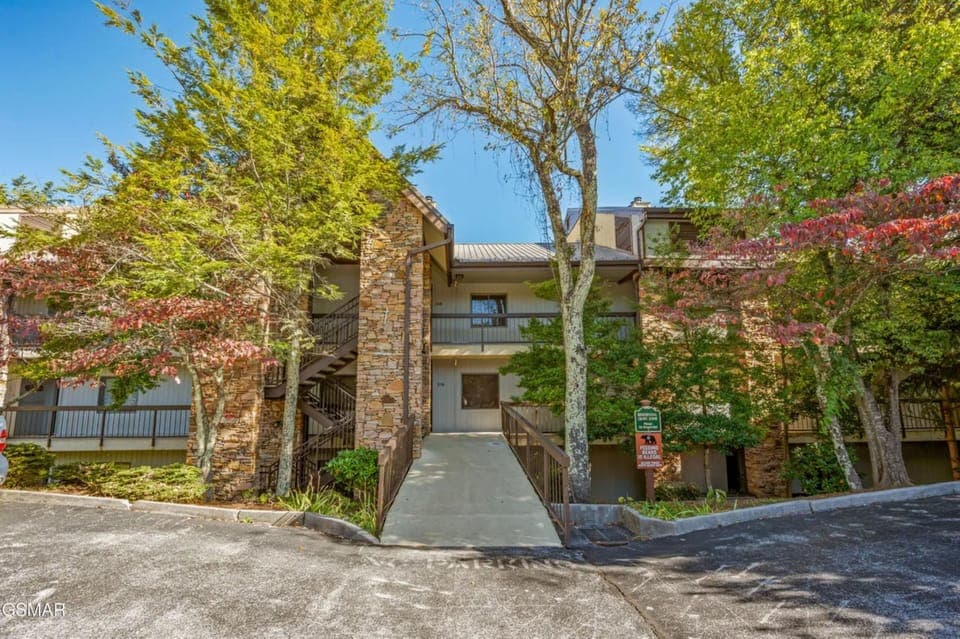 Modern multi-level building nestled among mature trees with convenient parking and accessible walkways for a comfortable arrival experience.