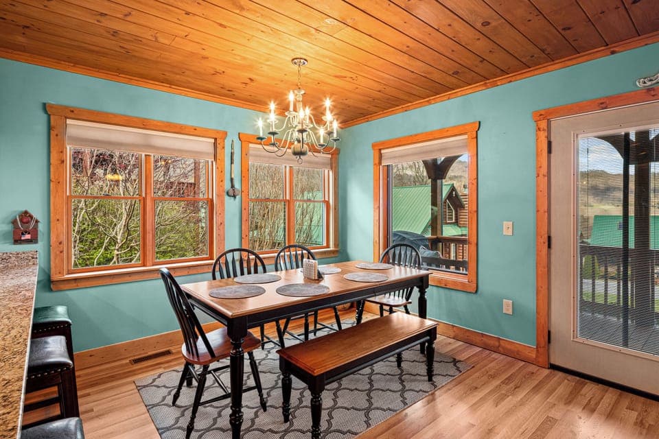 Dining area with turquoise walls, wood trim, chandelier, and mountain view.