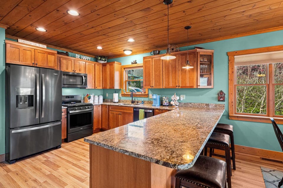 Modern kitchen with wood cabinets, granite counters, turquoise walls.