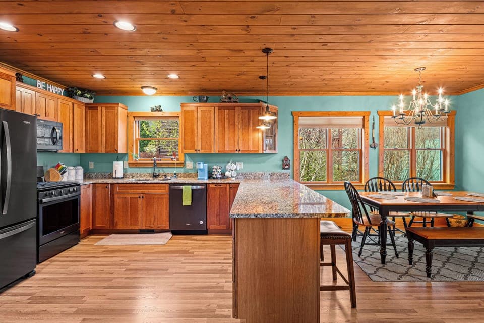 Kitchen and dining area with wood cabinets, granite counters, and turquoise wall