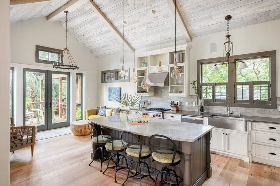 There is an open-concept living area and kitchen characterized by soaring 14-foot vaulted ceilings and washed reclaimed-wood beams