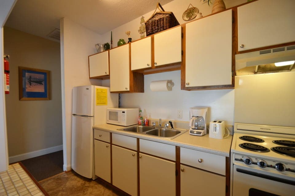 Galley kitchen with ceramic tile floor and open pass through to dining area
