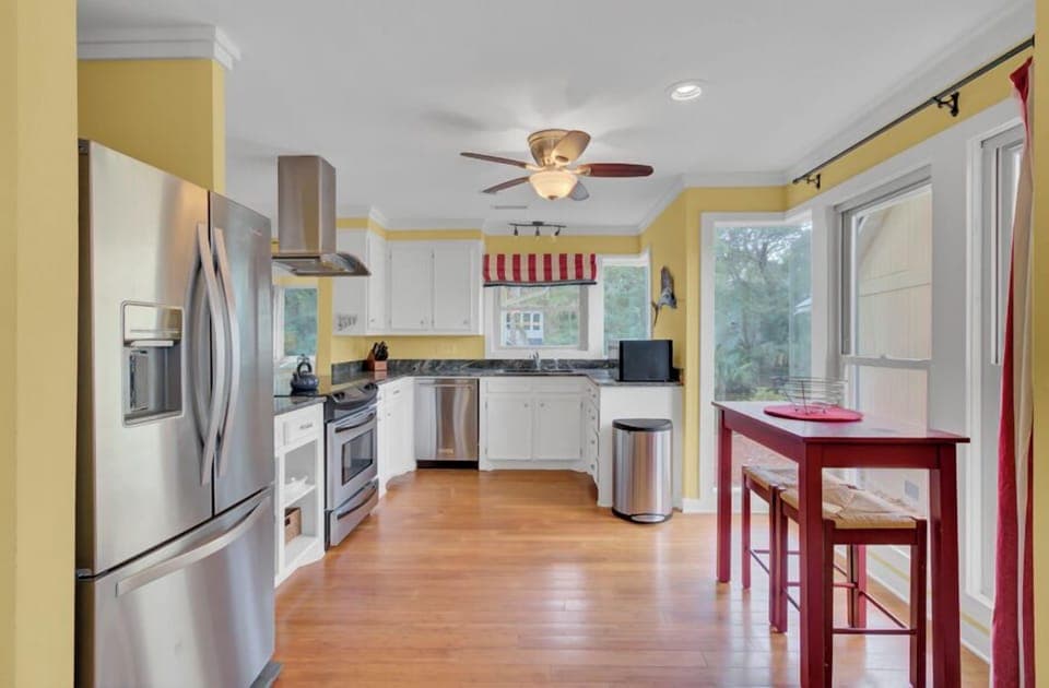 Gather in your bright, fully-equipped kitchen featuring stainless steel appliances, white cabinetry, and warm wood floors perfect for morning coffee.