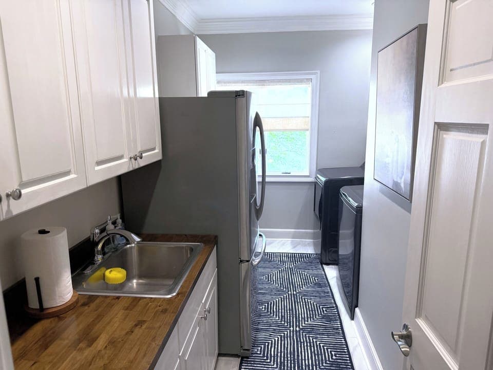 Laundry room with washer, dryer, extra refrigerator, and sink.