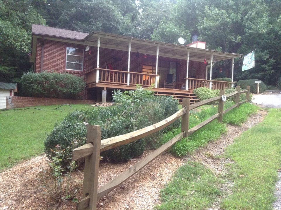 The split rail fence and side porch welcomes all to the Cozy Cabin.