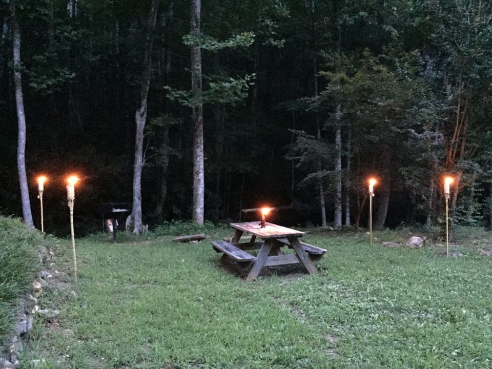 Picnic area with charcoal grill next to stream.