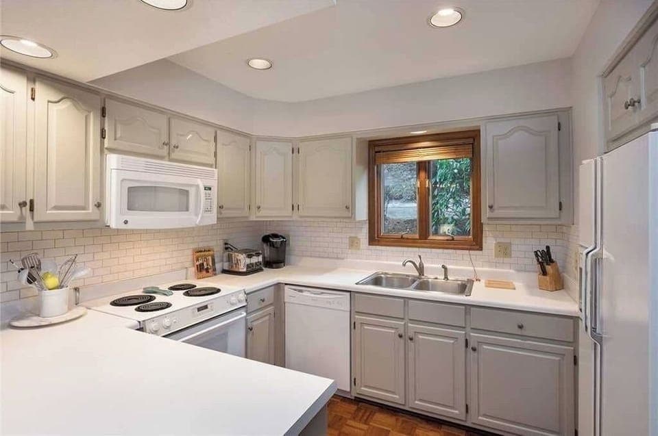 Fully stocked kitchen with grey cabinets and white subway tile 