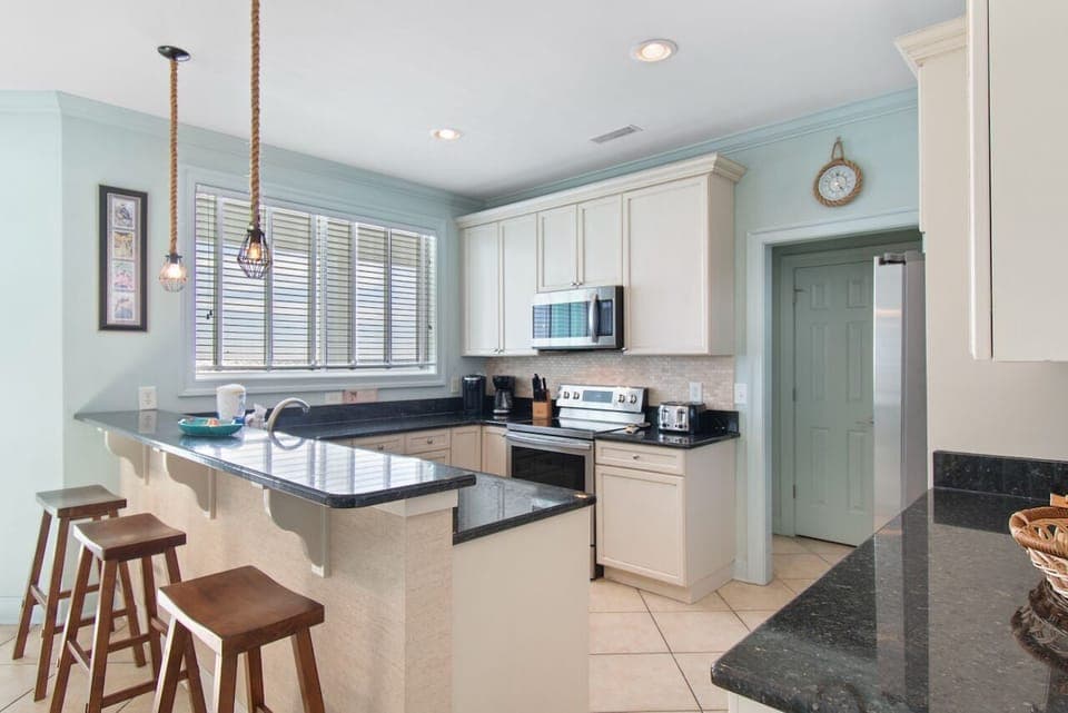 Your coastal-inspired kitchen awaits with granite counters, breakfast bar seating, and full appliances for home-cooked meals during your stay.