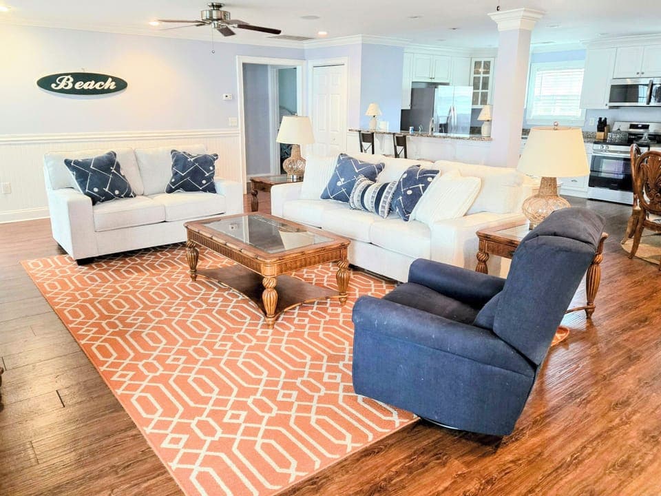 Sink into plush coastal comfort in your spacious living area, where nautical blues meet warm woods and beach vibes welcome you home.
