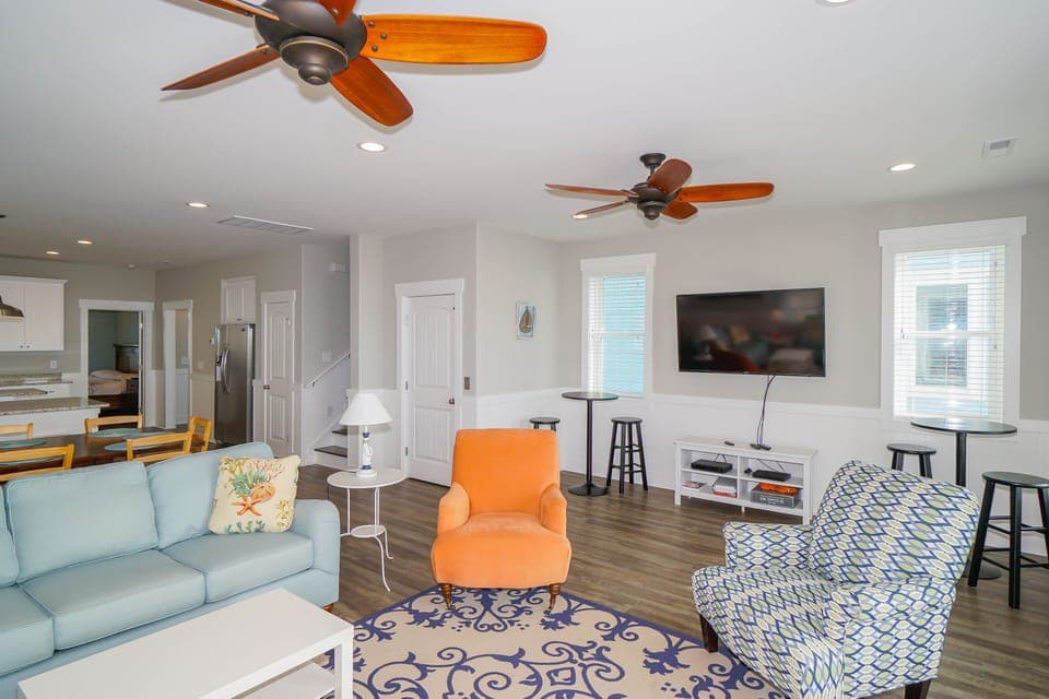 Relax in your bright, airy living space with comfortable seating, large TV, and ceiling fans keeping you cool.