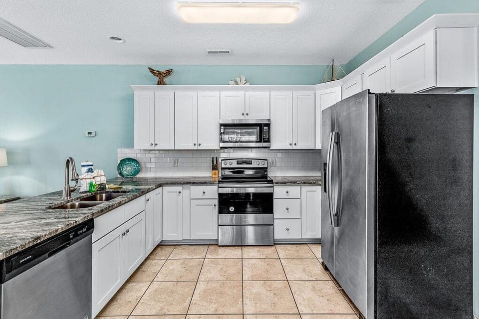 Your fully equipped kitchen features granite counters, stainless appliances, and soothing coastal colors perfect for preparing meals.